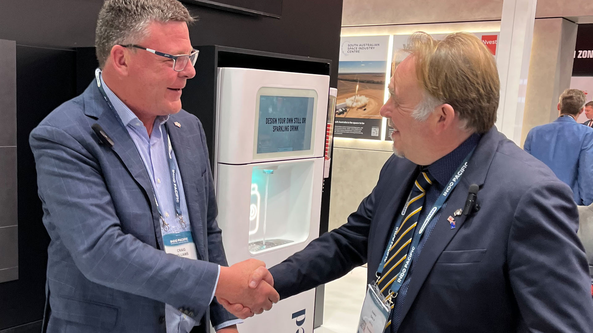 Photo of two men in suits shaking hands at an event.