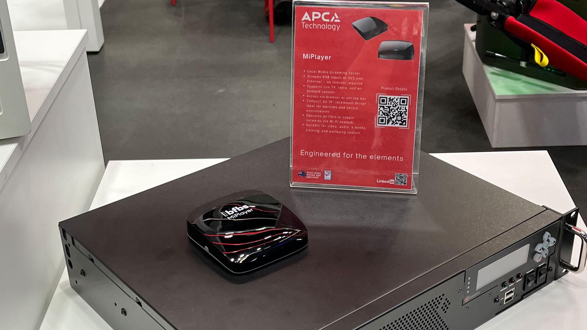 Close image of the BFBS MiPlayer, a small black device sat on top of a machine.