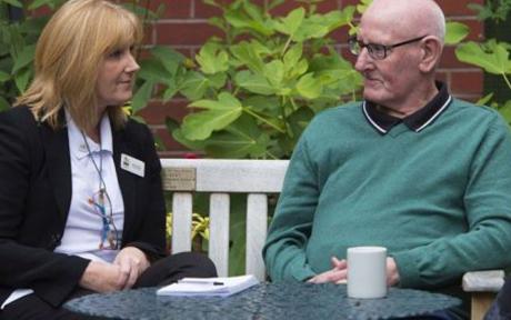 Two people chatting outside at a coffee table.