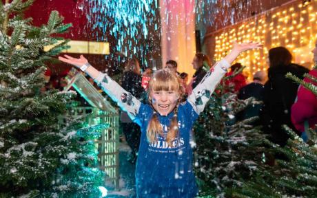 Girl with arms wide open as snow falls.