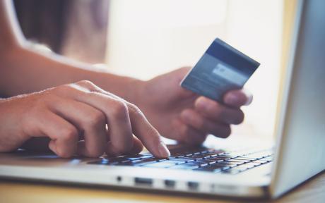 Online shopping. Close up of a hand holding credit card and using laptop.