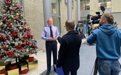 Man next to Christmas tree with presenter and camera person