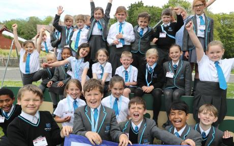 Group of school children smiling and cheering, group shot.