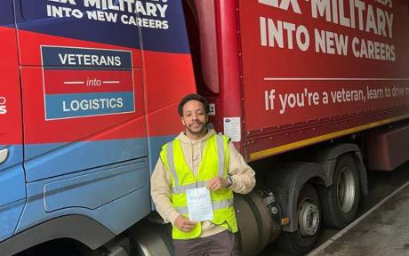 Ex-Royal Engineer, Reuben Clarke stood infront of a lorry holding a certificate.